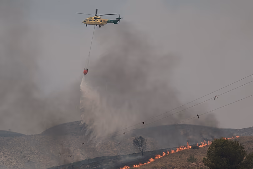 A helicopter drops water while fighting a wildfire in Los Gallardos, near Almeria, Spain, Friday, July 10, 2026.