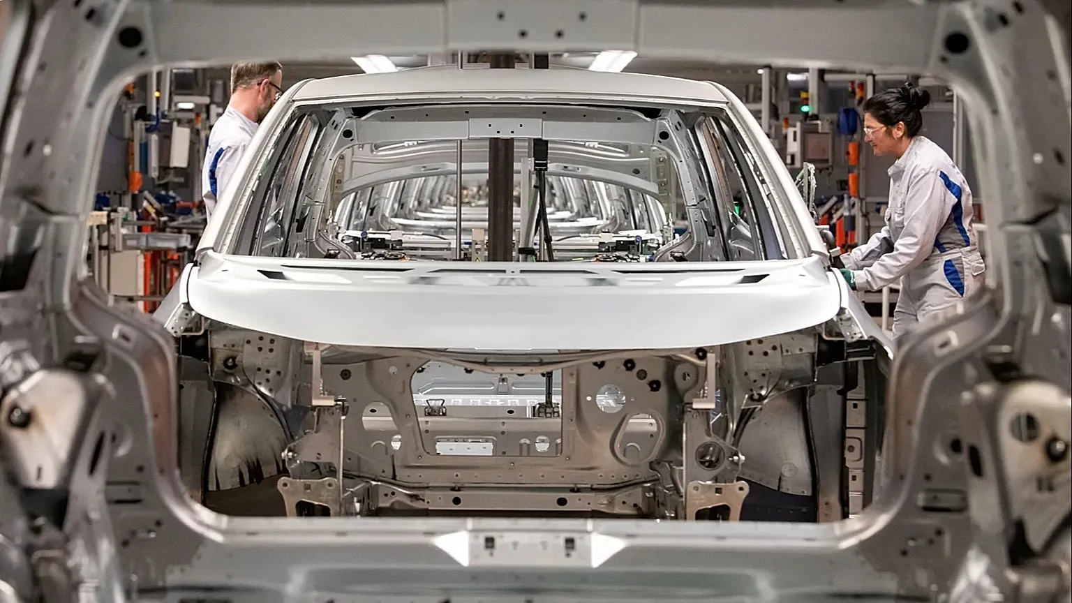 Workers complete an electric car on an assembly line during a press tour at a Volkswagen AG plant in Germany.