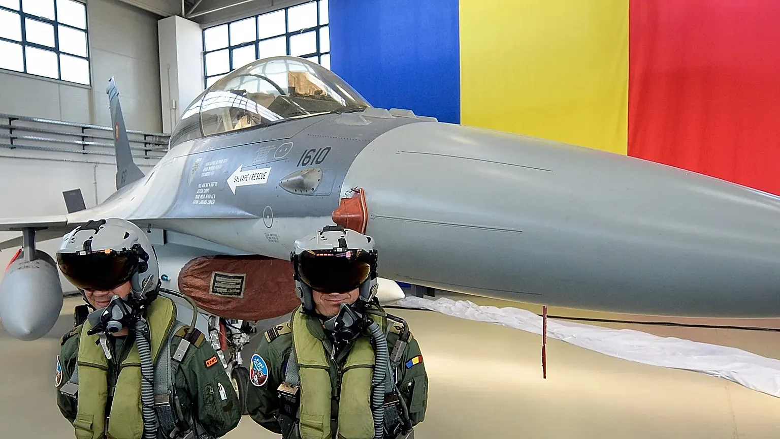 Romanian pilots stand next to a Romanian Air Force F16 fighter jet parked inside a hangar of the Air Base 86, in Borcea, southern Romania, Friday, Oct. 7, 2016.