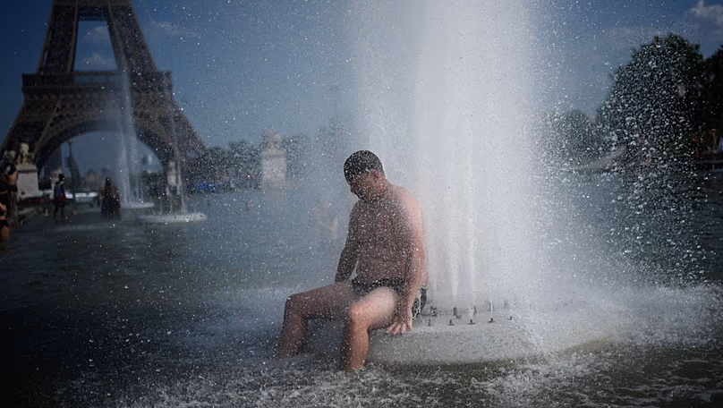 A person cools off at Trocadero fountain near the Eiffel Tower during a heat wave in Paris, 24 June, 2026