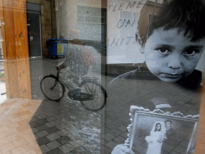 Reflejo de un hombre en bicicleta frente a una foto cubierta de vidrio de un niño sujetando la imagen de su padre desaparecido durante la invasión turca de 1974, Nicosia, 27 de enero de 2009