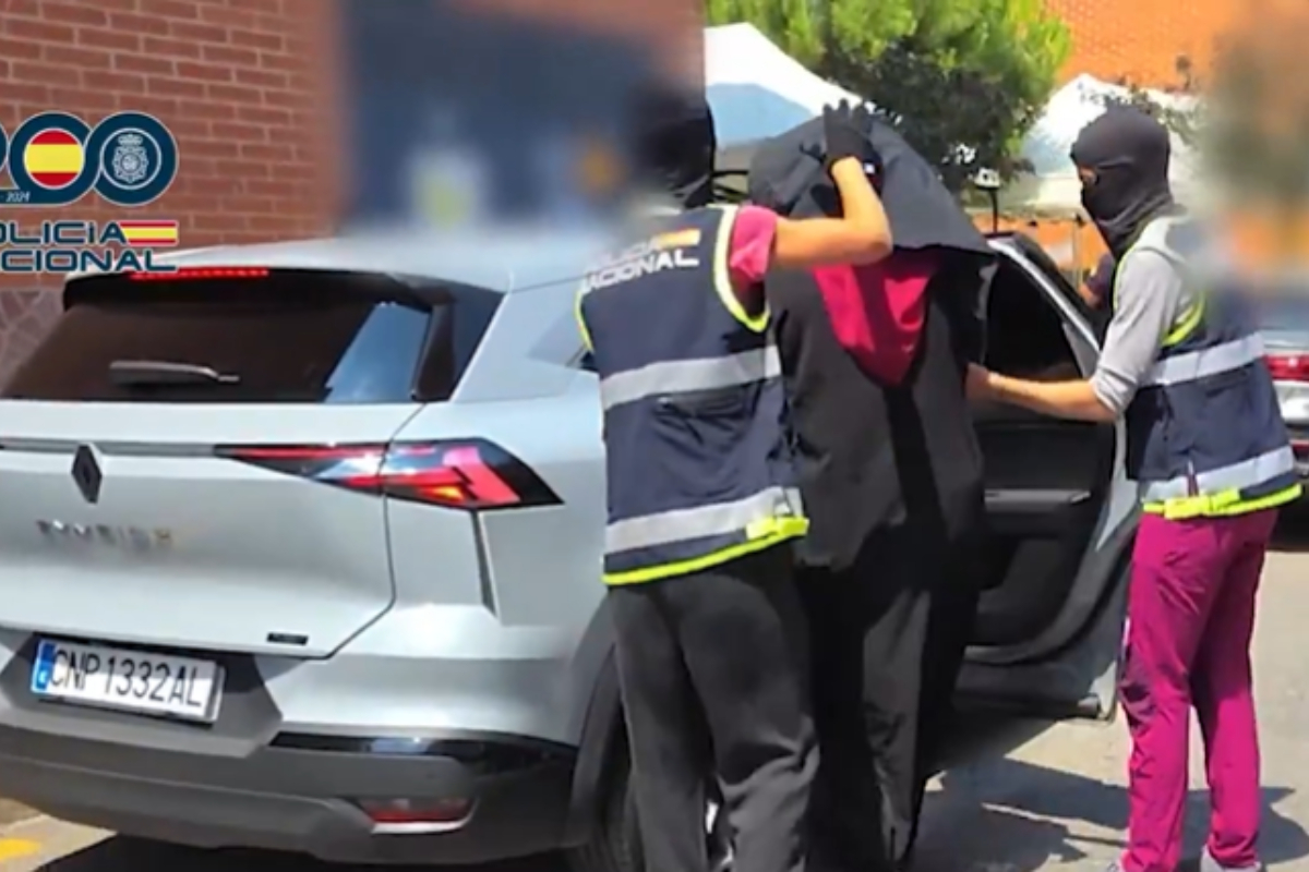 Dos agentes meten en un coche a uno de los detenidos.