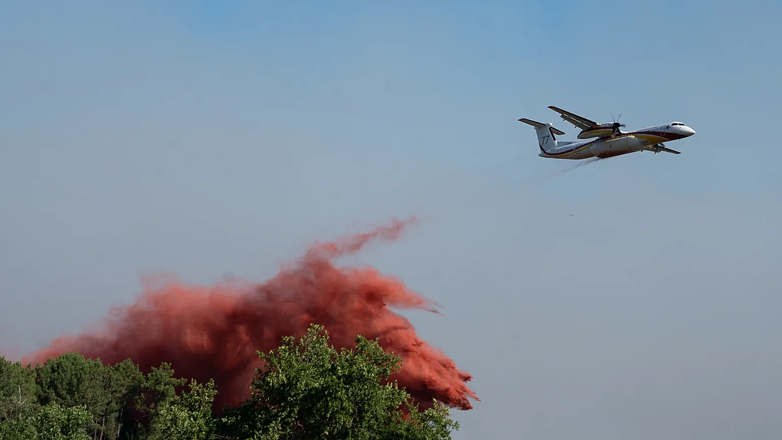 A water bomber drops water while fighting wildfires In Ares, western France, Friday July 24, 2026. (AP Photo/Caroline Blumberg)