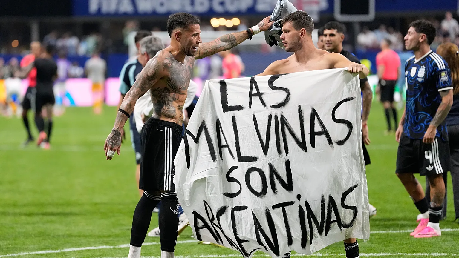Argentina's Giovani Lo Celso holds a banner with the words "The Malvinas are Argentine" next to teammate Nicolas Otamendi. 
