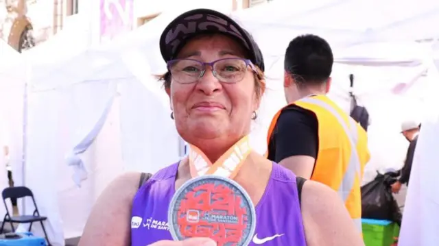 Elisabeth Osorio mostrando la medalla que ganó al terminar la maratón.