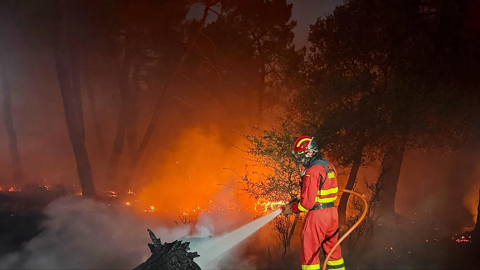 Two firefighters struggle to put out the flames.