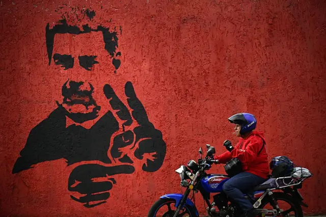 Un motorista pasa junto a un mural con la imagen de Nicolás Maduro.