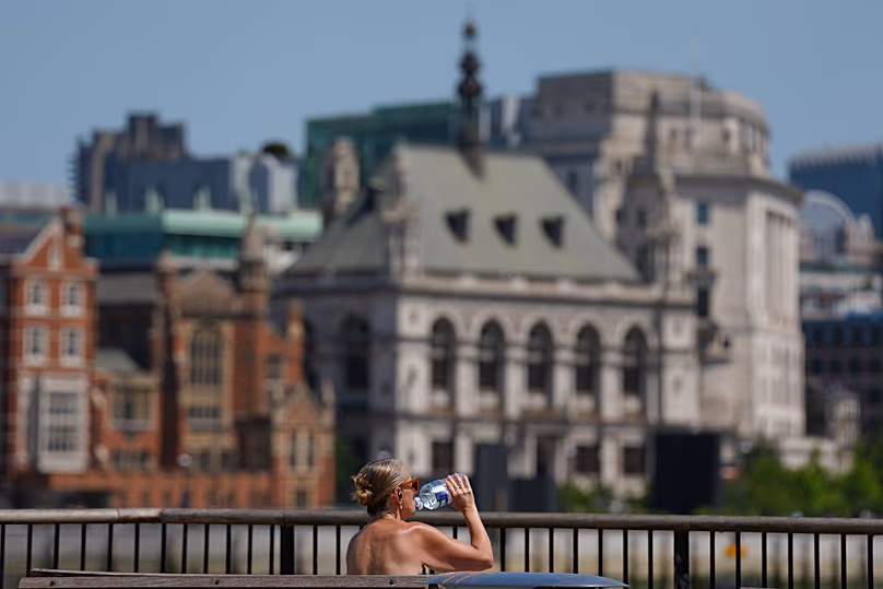 A woman takes a drink in London as a heatwave is predicted, 23 June, 2026