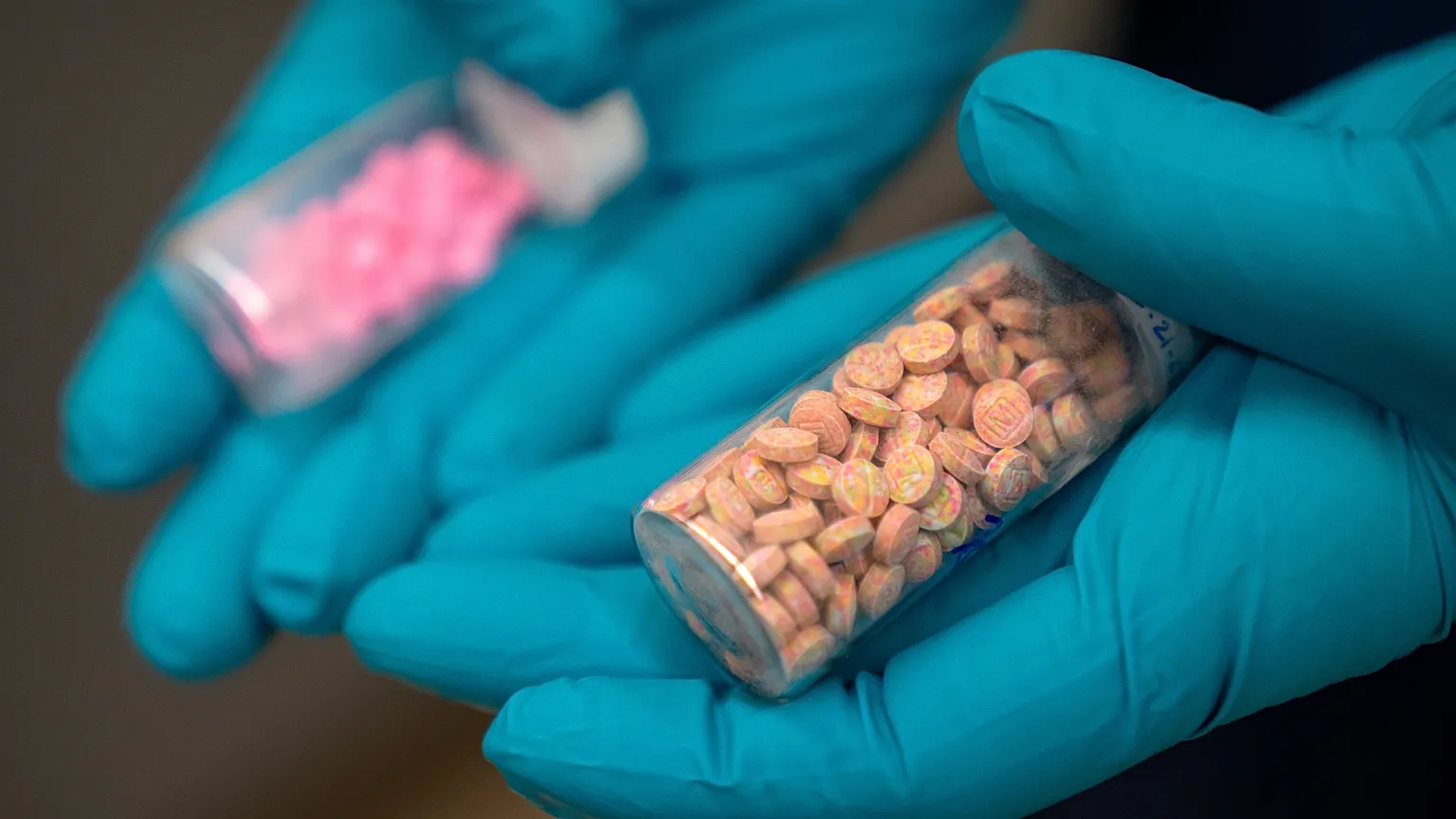 Jonathan Dumke, a senior forensic chemist with the Drug Enforcement Administration, holds vials of fentanyl pills at a DEA research laboratory on April 29, 2025