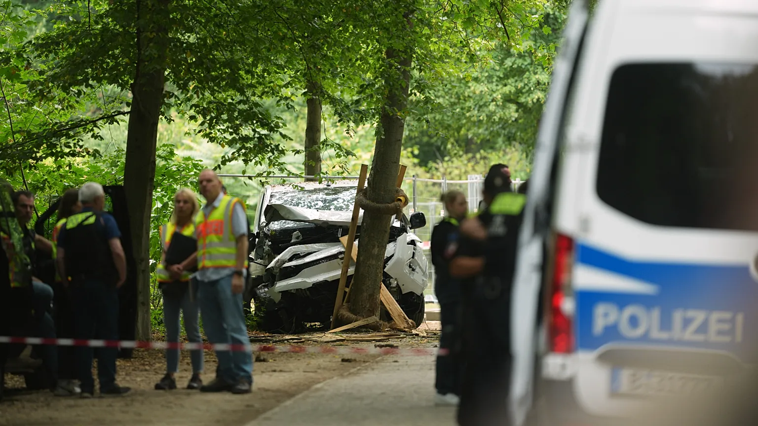 Police officers stand near a vehicle crashed into a tree after driving into a crowd near Berlin's annual Pride event, in Berlin, Germany,