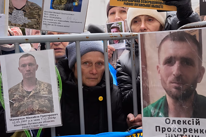People hold photos of their relatives as Ukrainian soldiers return from captivity during a POW exchange in Chernyhiv region, 11 April, 2026