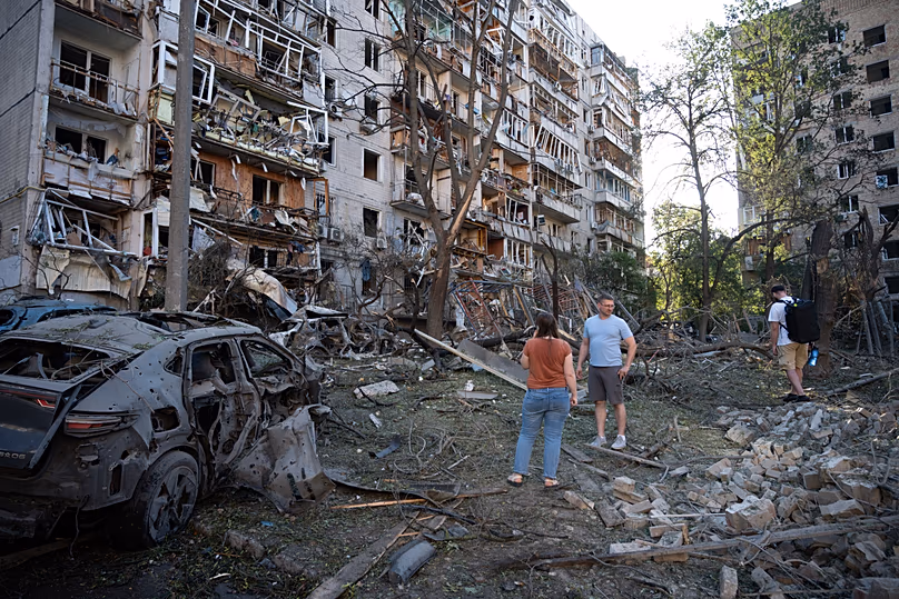 People look at a residential building damaged during the Russian missile attack in Kyiv, 2 July, 2026