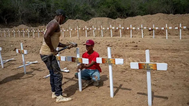 Una persona pone una cruz en el cementerio La Esperanza