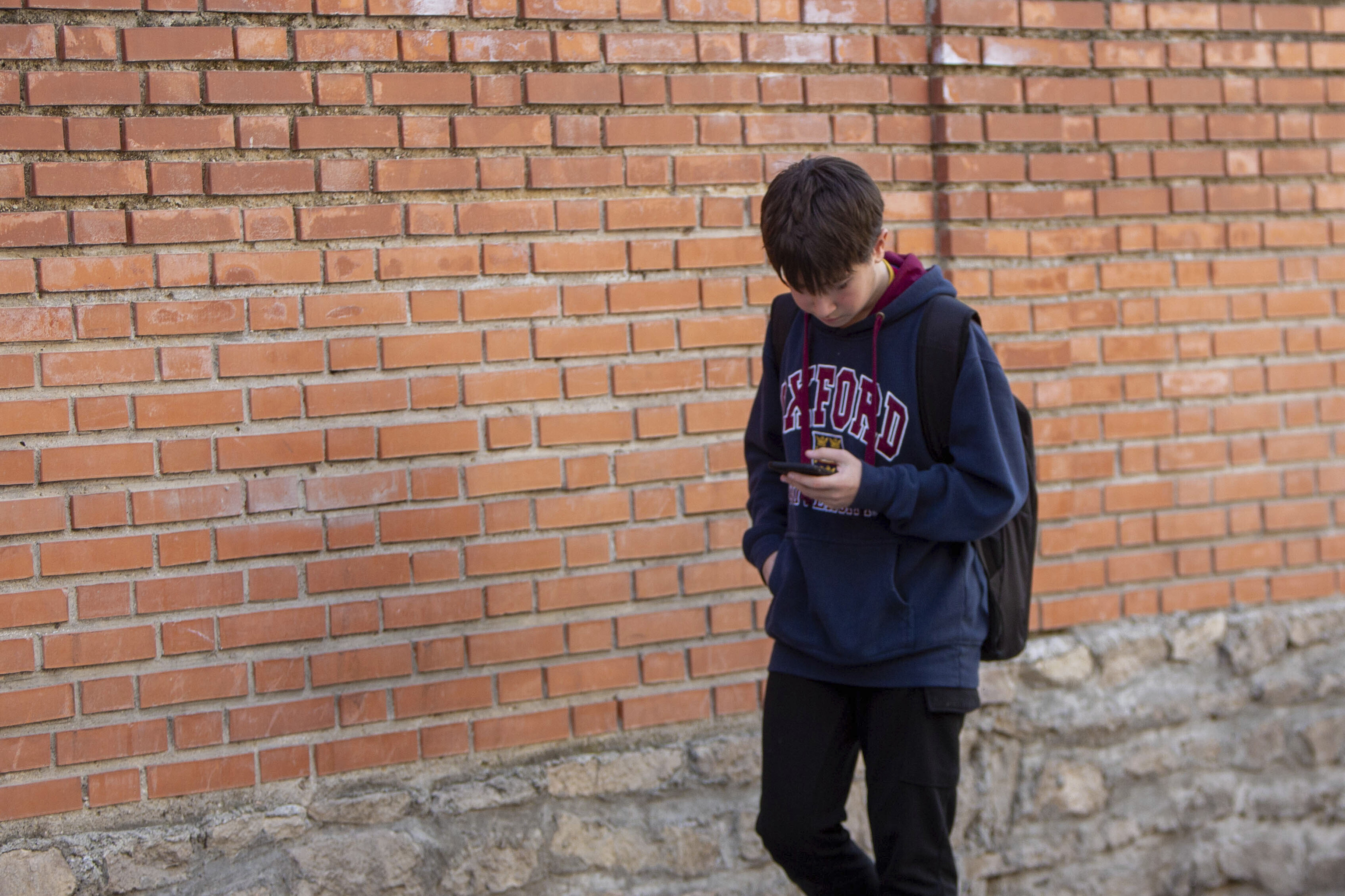 Un alumno camina mirando al móvil en Madrid.