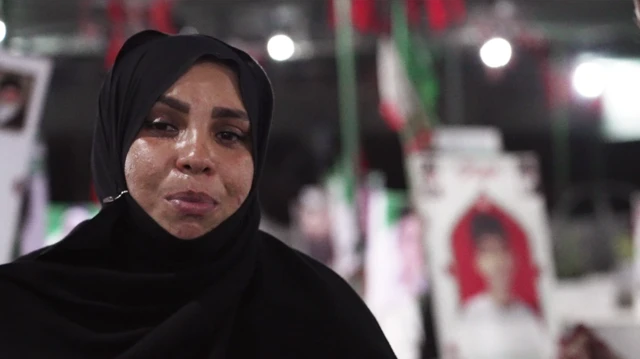 Masoumeh Mehran Shekhabadi aparece en la fotografía con un chador negro y una expresión triste. Detrás de ella se aprecian imágenes desenfocadas de niños sobre tumbas en el cementerio.