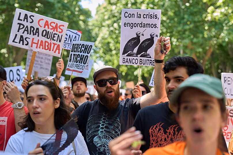 People hold a banner, top left, reading in Spanish: "Homes for those who live in them" during a protest in Madrid, Spain, Sunday, May 24, 2026.