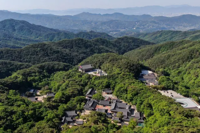 Vista aérea del templo de Donghwasa, rodeado de un denso bosque en las montañas cercanas a Daegu, Corea del Sur