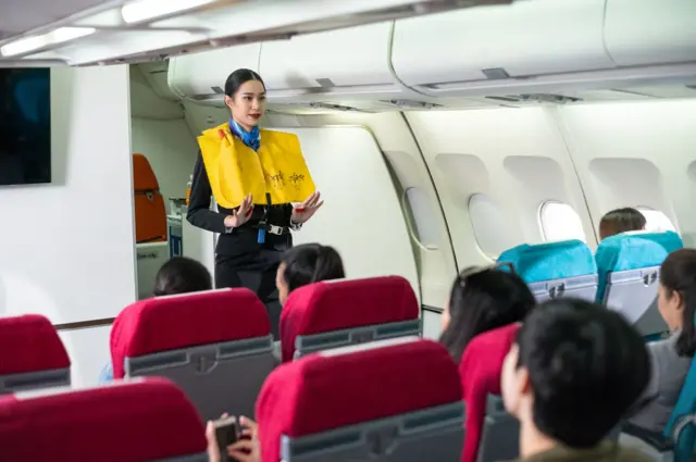 Una azafata explica el uso de los chalecos salvavidas en un vuelo.