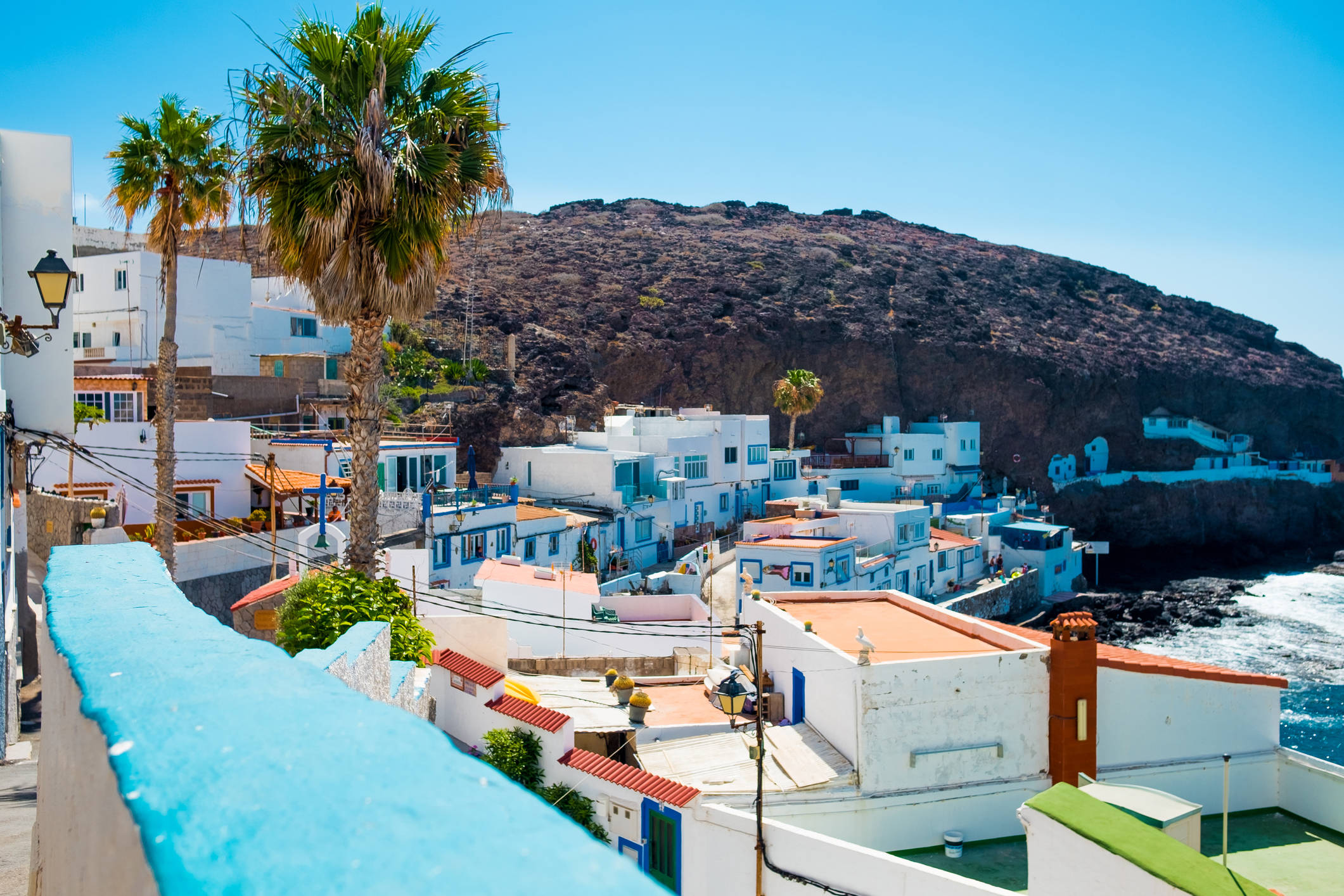 Foto: Las características casas blancas de este rincón de Gran Canaria contrastan con el paisaje volcánico y el azul del océano. (iStock)