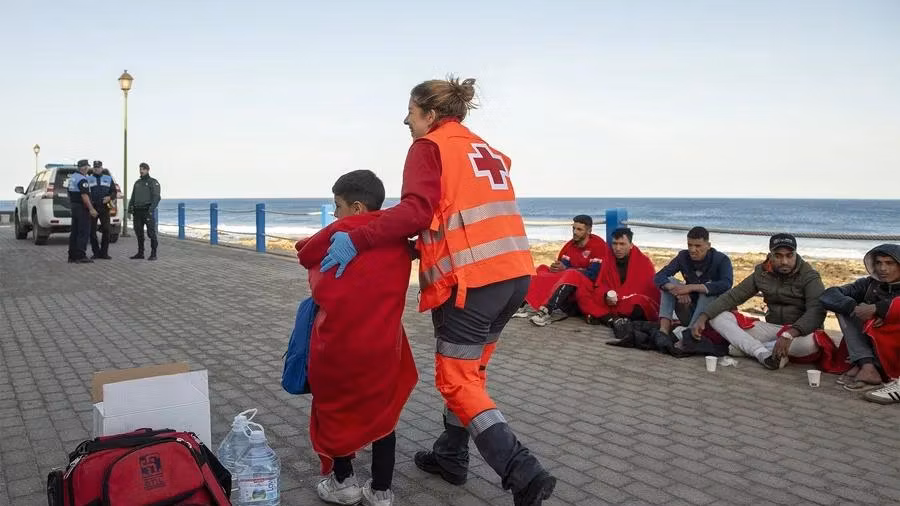 Mujer de la Cruz Roja acompañando a un menor. EFE