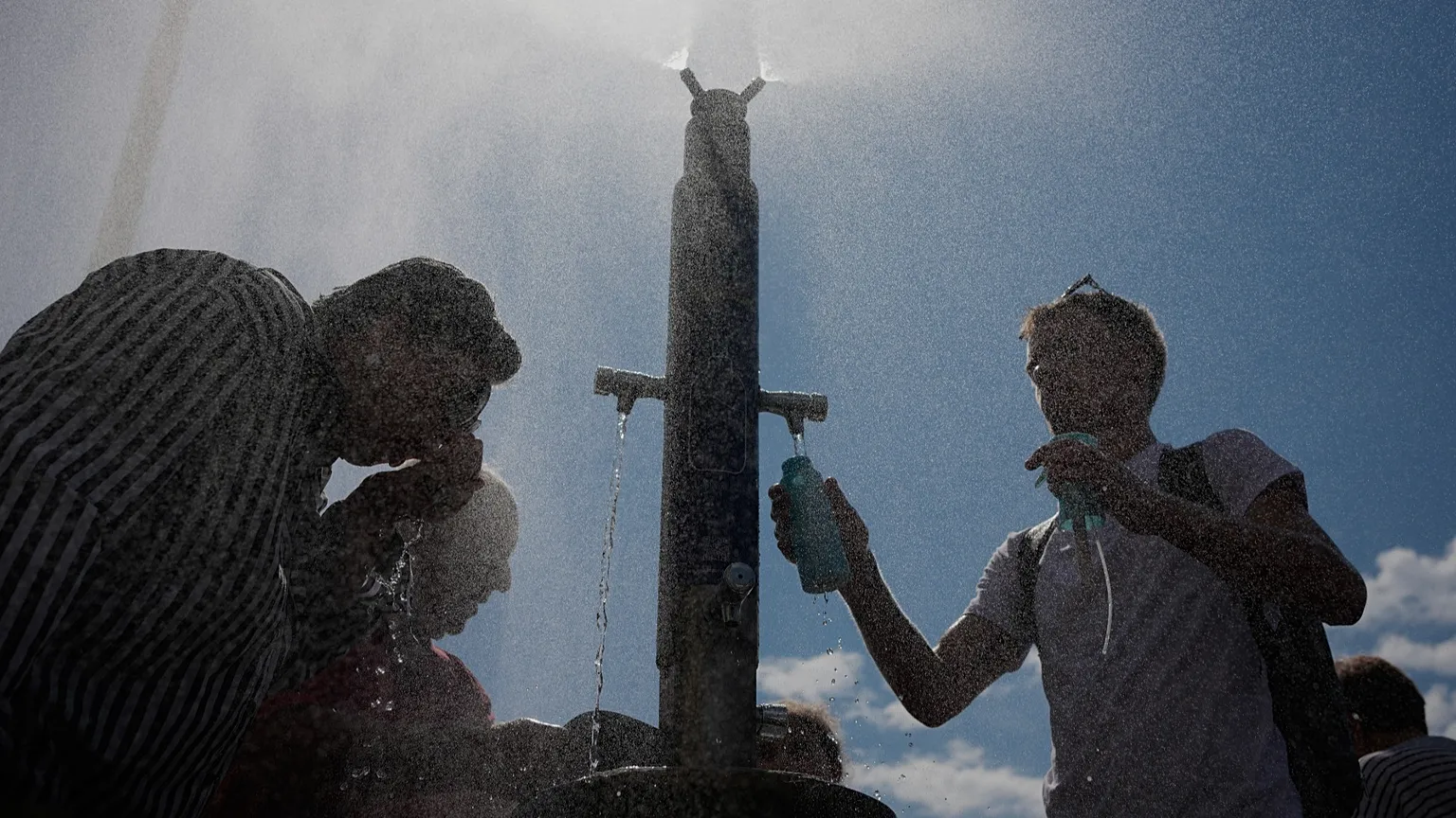 Tourists cool off at a public water fountain in Paris, 26 June, 2026