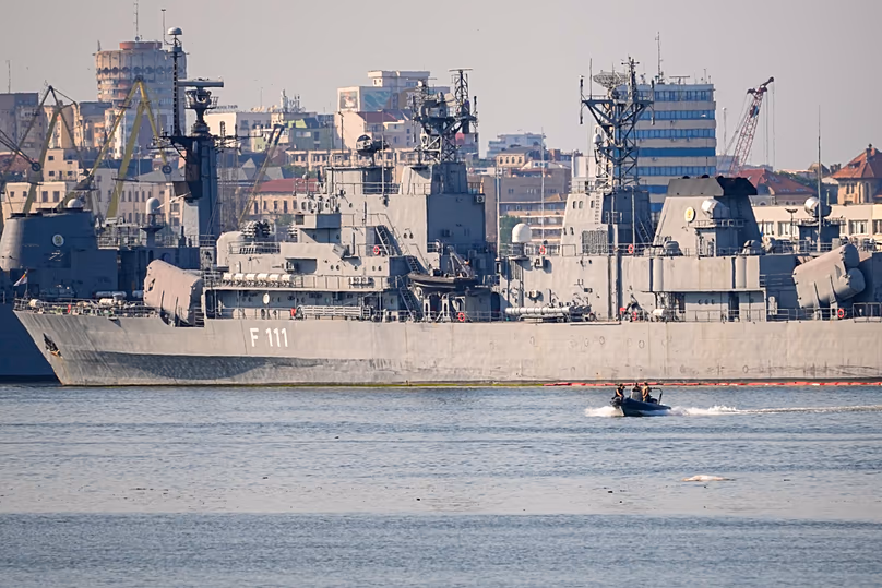 A small military patrol boat sails past the Romanian frigate Marasesti docked in the military port of Constanta following the explosion of a maritime drone.