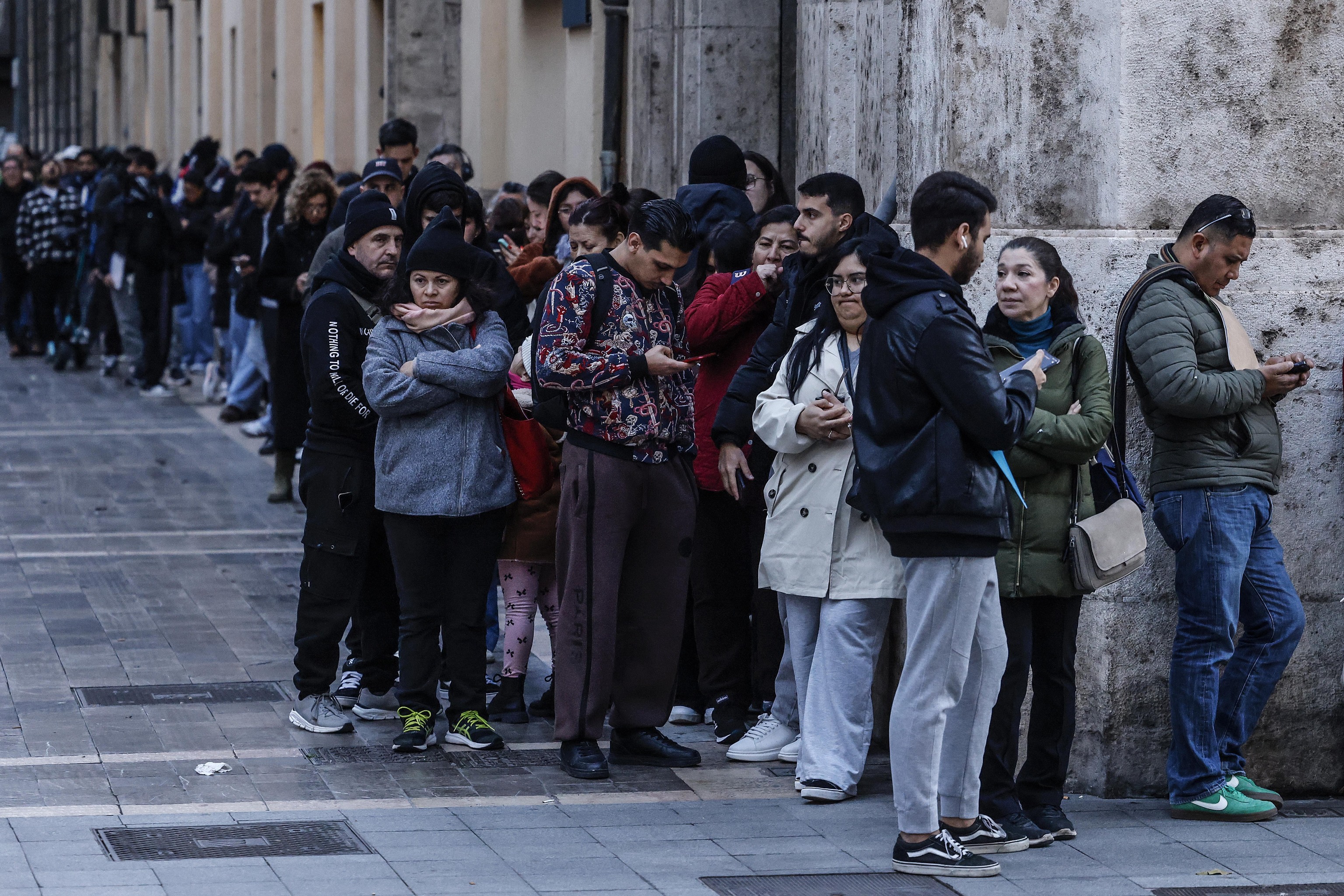 Inmigrantes hacen cola en el Ayuntamiento de Valencia para tramitar la regularización.