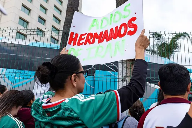 Mundial de fútbol. Señora sostiene un cartel que dice "Adios hermanos de Irán".