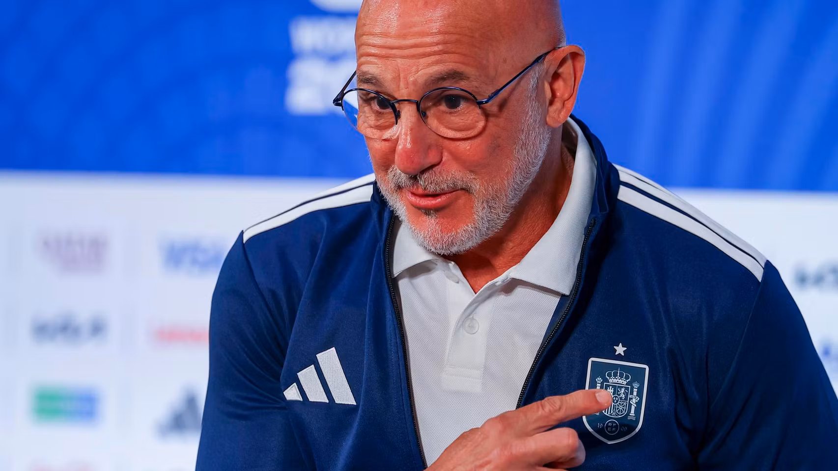 Luis de la Fuente, señalándose el escudo de la Selección en la sala de prensa.