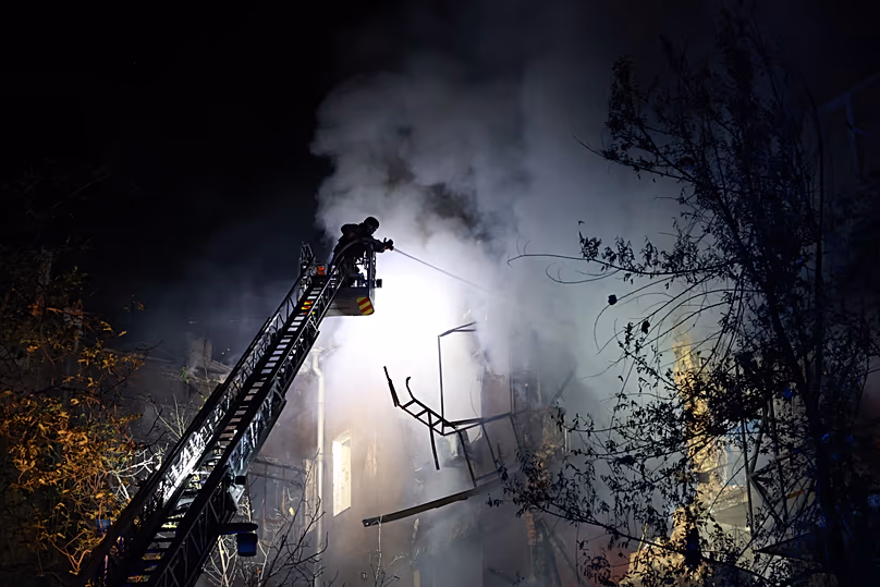 Rescue workers try to put out a fire of a residential building burning after a Russian drone attack on Zaporizhzhia, 12 July, 2026