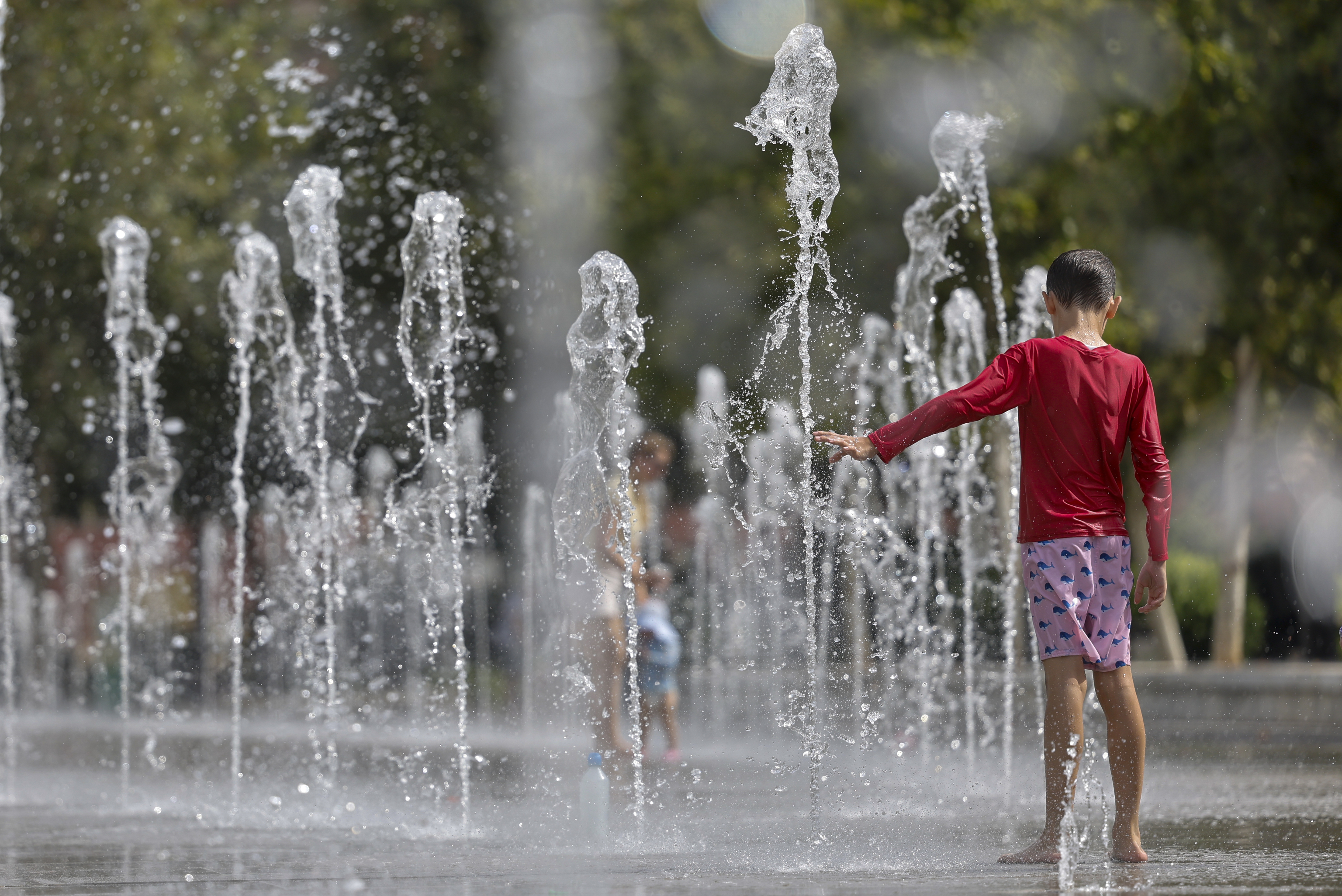 Un niño se refresca en una fuente de Valencia.