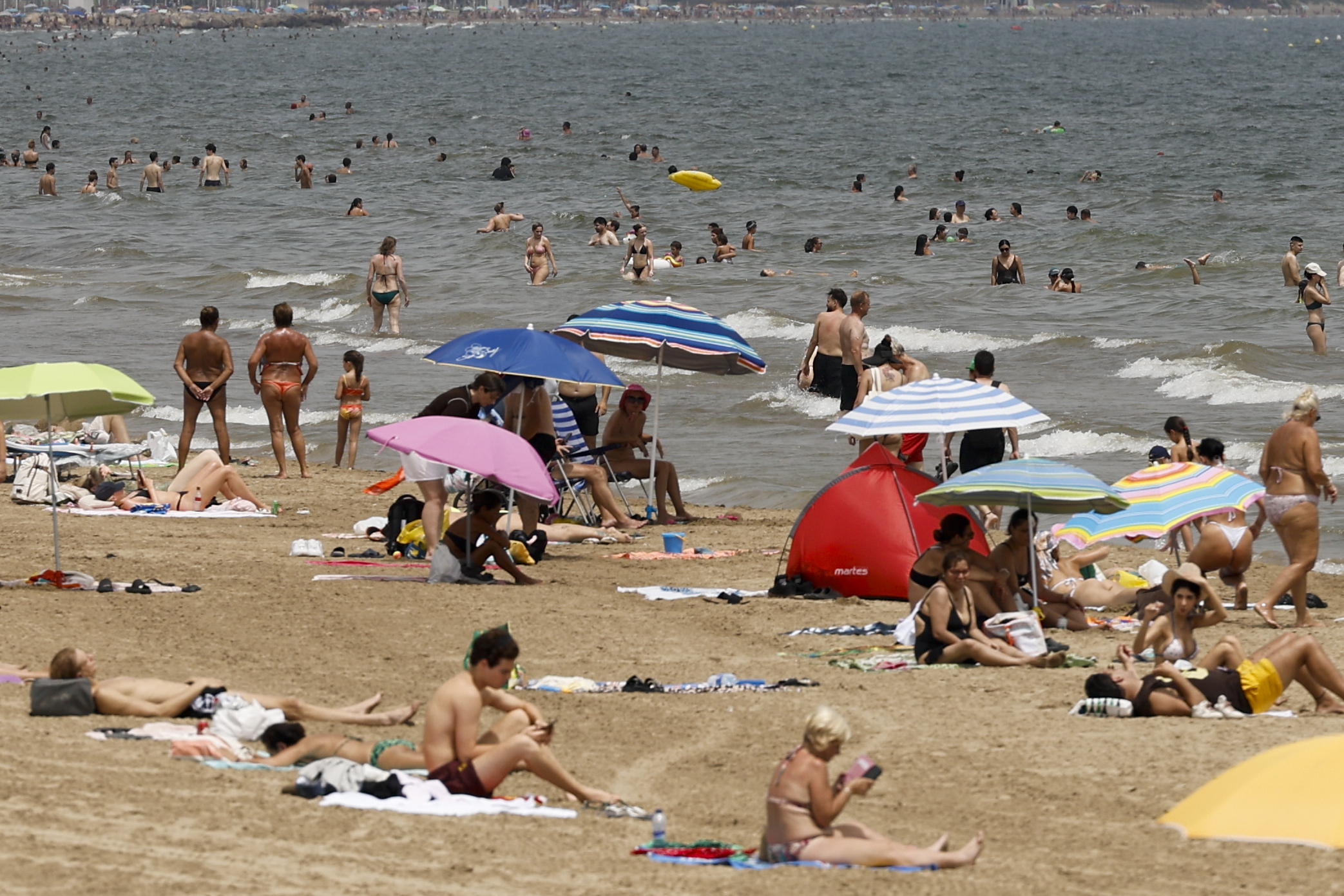Un gran número de personas combaten el calor en la playa de la Malvarrosa durante este lunes.