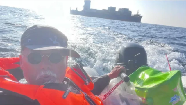 Dong Guangping se toma una foto con un chaleco salvavidas naranja mientras navega en un bote en el mar.