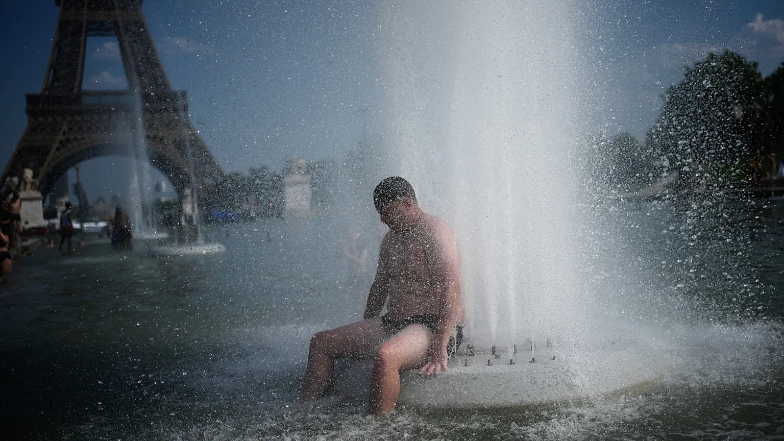 People cool off at Trocadero fountain near the Eiffel Tower during a heat wave in Paris, Wednesday, June 24, 2026. (AP Photo/Christophe Ena)