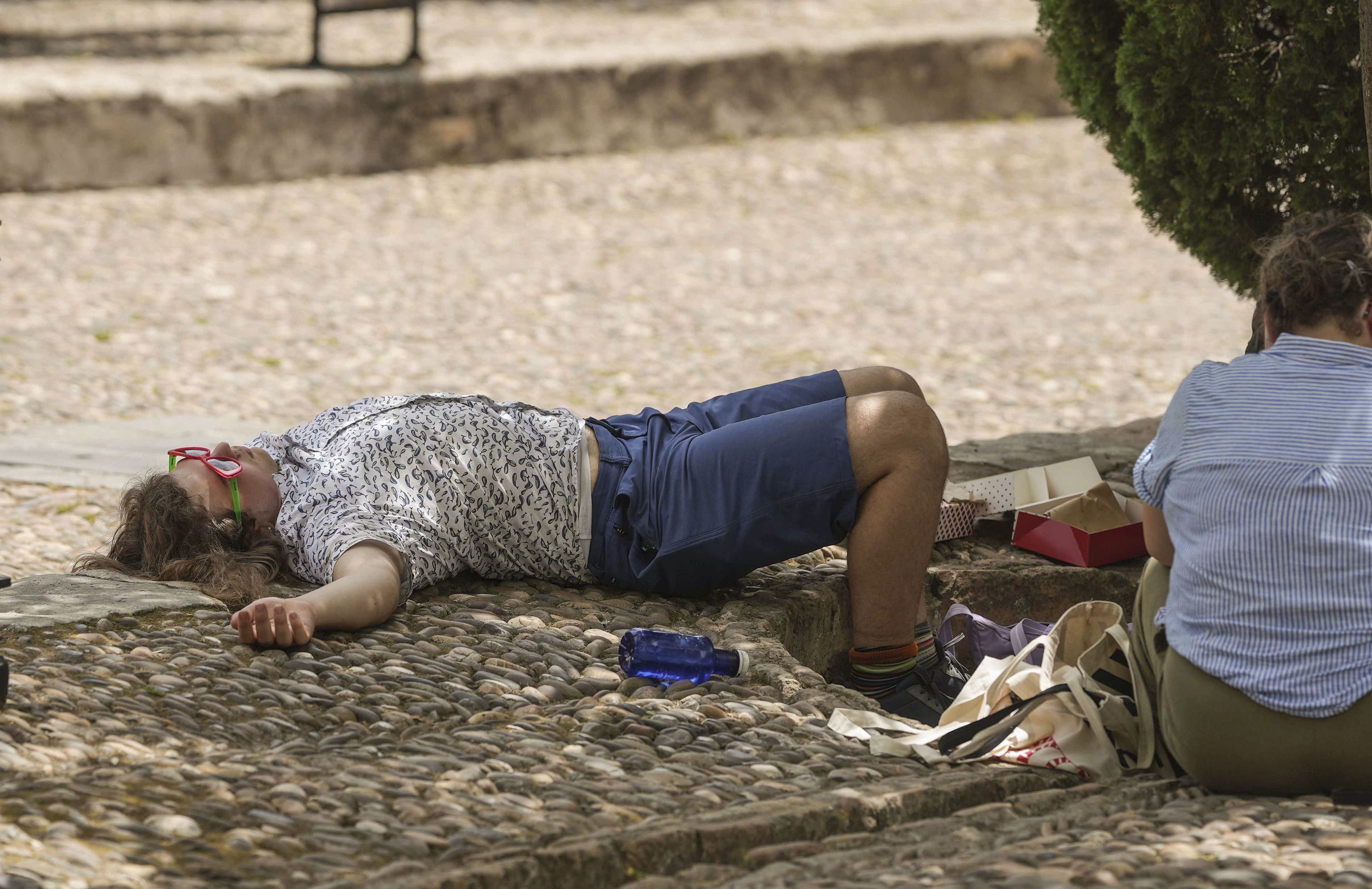 Una mujer descansa junto a su botella de agua en un caluroso día en Córdoba.