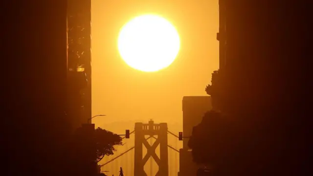El sol sale tras el puente de la bahía de San Francisco-Oakland en San Francisco, California.