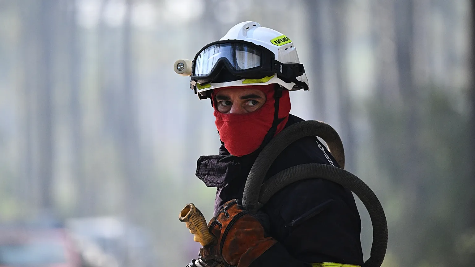 A firefighter carries his equipment as he works to suppress a fire in a forest in Claouey, during wildfires in the area of southwestern France, Tuesday, July 28, 2026. 