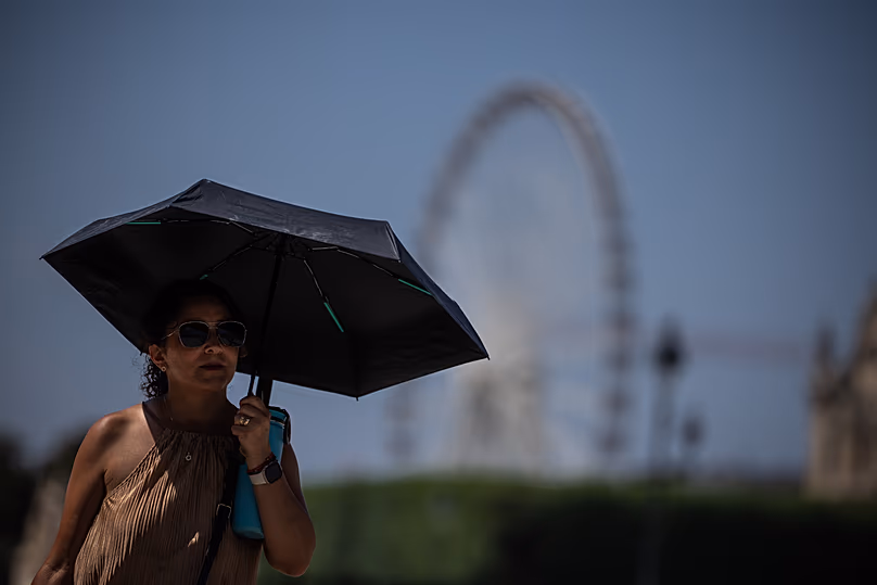 Un turista con paraguas camina en París durante una ola de calor, 27 junio, 2026