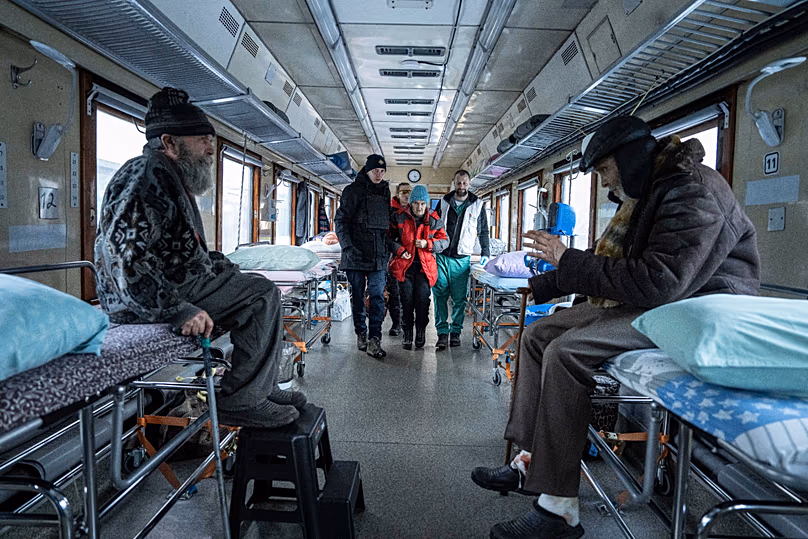 Medics help a woman take a seat inside the MSF medical train in Pokrovsk, 14 February, 2023