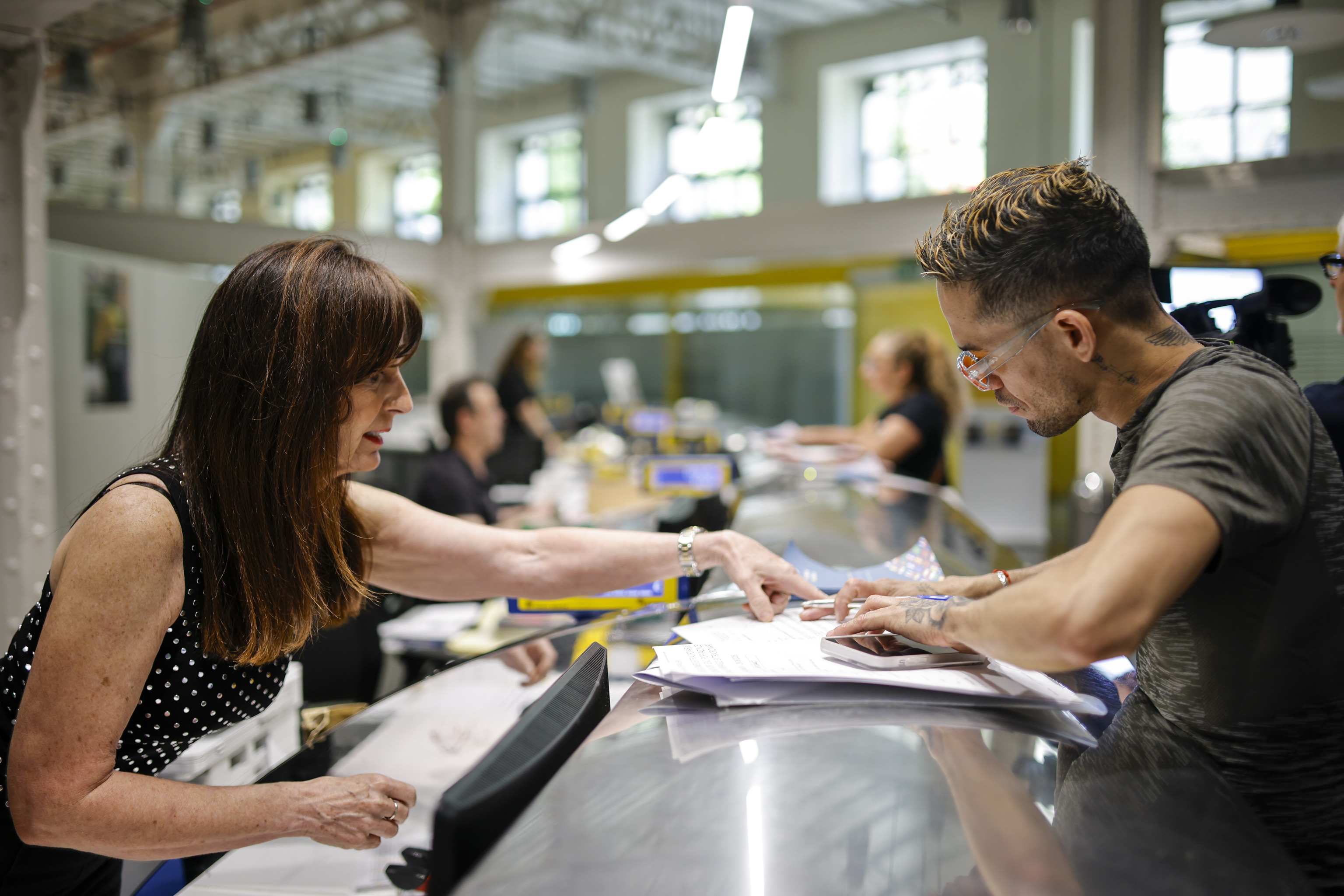 Una funcionaria en una oficina de Correos recoge la solicitud de una persona para acogerse a la regularización.