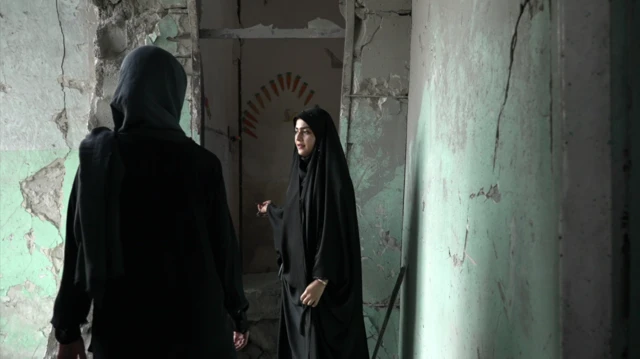 Amaineh Nademi camina por uno de los pasillos que aún se conservan de la escuela primaria Shajareh Tayyebeh en Minab. Viste un chador negro y le muestra a Nawal al Maghafi, reportera de la BBC, los daños en la escuela. Las paredes de hormigón están agrietadas y anteriormente habían sido pintadas de verde pastel.