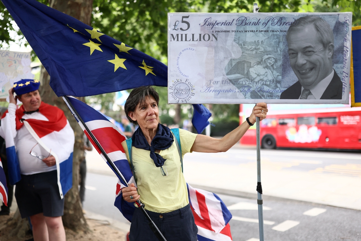 Una mujer sostiene un cartel con una imagen de Farage que referencia la investigación en curso en una movilización crítica con el Brexit. (REUTERS/Jack Taylor)
