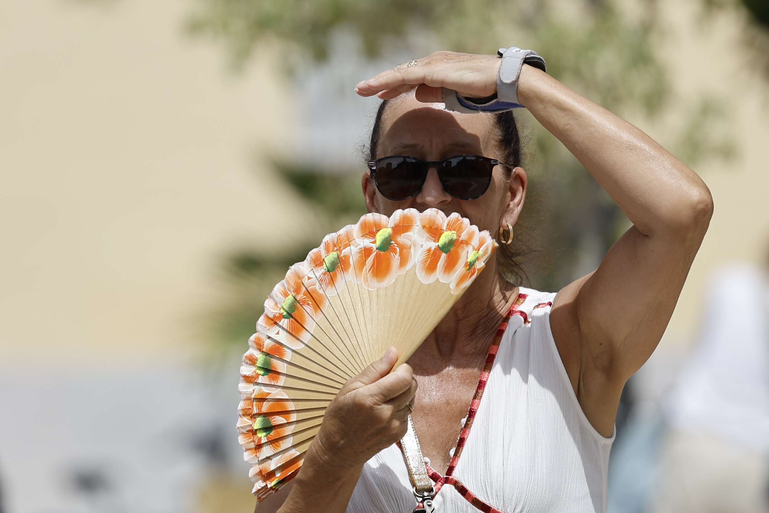 Una mujer se protege del sol con un abanico en Valencia.