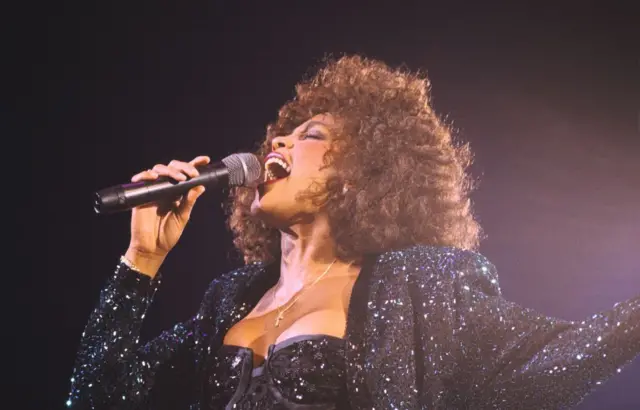 Whitney Houston interpretando una canción en el escenario