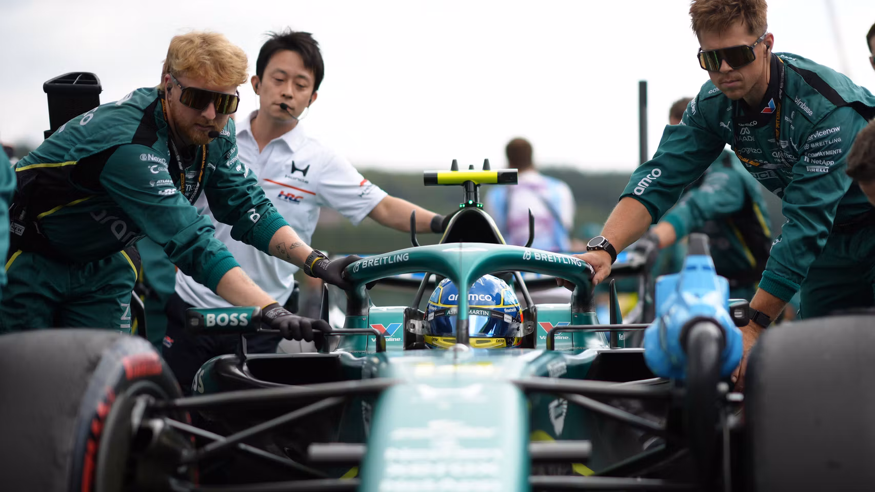 Los mecánicos de Aston Martin llevan el AMR26 hasta la parrilla de salida.